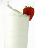 Milk splashing out of glass with strawberry