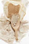 Wholemeal flour in sack with wooden scoop