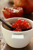 Pomegranate seeds in small bowl with spoon