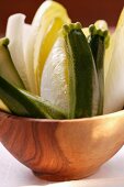 Courgettes and chicory in wooden bowl