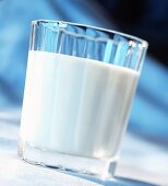 Glas Milch vor blauem Hintergrund