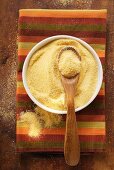 Polenta in bowl with wooden spoon on coloured cloth