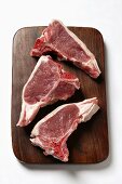 Three lamb cutlets on chopping board