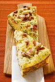 Two pieces of leek and bacon quiche on chopping board