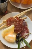 Salami, cheese, olives and grissini on plate