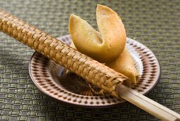 Fortune cookies and chopsticks in woven wrapper on plate