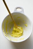 Remains of mashed potato on wooden spoon in bowl