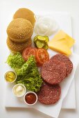 Ingredients for cheeseburgers on chopping board