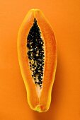 Halbe Papaya auf orangefarbenem Untergrund