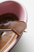 Schokoladenfondue mit Herzpraline auf Fonduegabel
