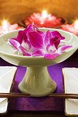 Thai table decoration: orchids in bowl of water, candles