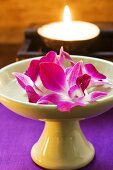 Thai table decoration: orchids in bowl of water, candle