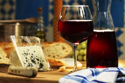 Rotwein in Glas und Karaffe und ein Stück Gorgonzola