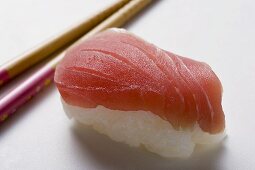 Nigiri-Sushi mit Thunfisch, daneben Essstäbchen