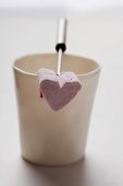 A heart-shaped marshmallow on a fondue fork resting on a mug