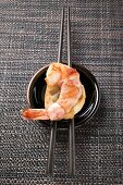 Bacon-wrapped king prawn on white bread and chopsticks