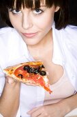 Junge Frau hält ein Stück Pizza