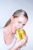 Young woman biting into a giant hamburger