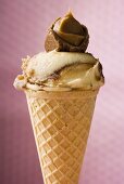 Caramel ice cream in wafer cone against pink background