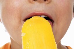 Boy eating orange ice lolly (close-up)