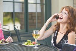 Brunette on phone at laid table on terrace