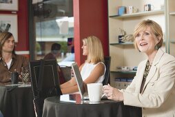 Frau mittleren Alters am Laptop in einem Café