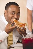 Mann beisst in ein Stück Pizza
