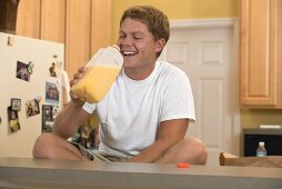 Man sitting in kitchen drinking orange juice