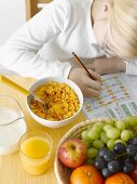 Girl with exercise book in front of healthy breakfast