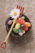 Coloured sweets in an Easter nest with toy pitchfork