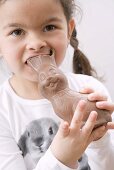Girl biting the ears of a chocolate Easter Bunny