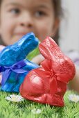 Two chocolate Easter bunnies in coloured foil in grass