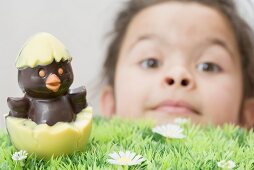 A girl with a chocolate chick hatching out of an egg