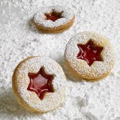 Three Linzer biscuits on icing sugar