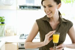 Junge Frau mit einem Glas Orangensaft in der Küche