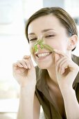 Young woman holding rocket leaf across her nose