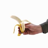 Hand holding a half-peeled banana