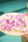 Hand holding a tray of flower petals at a swimming pool