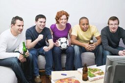 Freunde mit Fussball, Bier und Pizza sitzen vor dem Fernseher