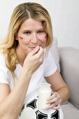 Young woman with football eating natural yoghurt