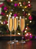 Drei Gläser Champagner, im Hintergrund Weihnachtsbaum