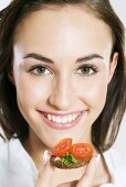 Young woman eating cherry tomato on pumpernickel