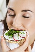Young woman eating open sandwich on wholemeal bread