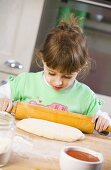 Small girl rolling out pizza dough