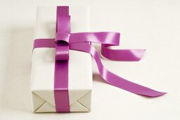 Gift in white wrapping paper with purple ribbon