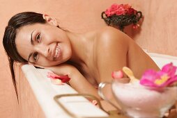 Young woman in bath with flower petals