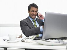Telefonierender Geschäftsmann deutet auf den Bildschirm