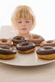 Little girl sitting in front of a plate of doughnuts