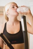 Blond woman drinking mineral water during workout