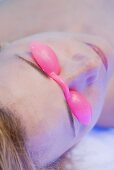 Blond woman in tanning goggles lying on tanning bed